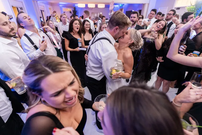 Ashley and Craig celebrate on the dance floor amid cheering guests in formal attire.