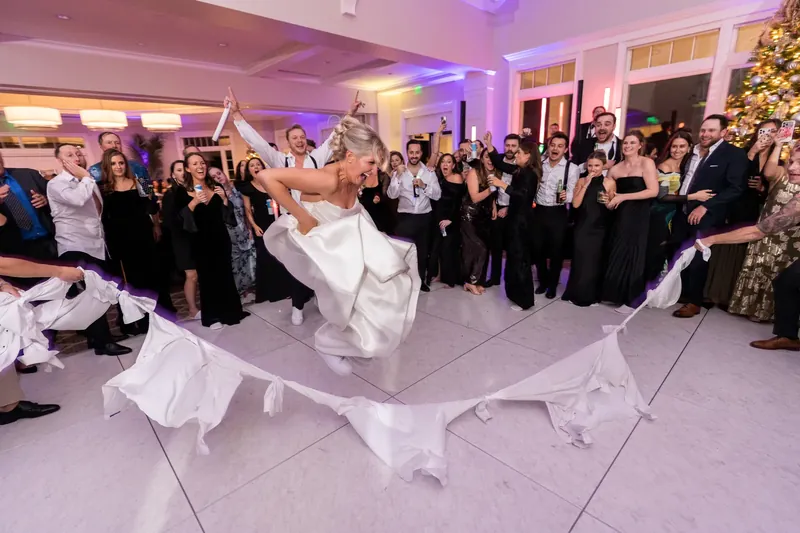 Ashley spins across the dance floor in a flowing white gown surrounded by watching guests in black.
