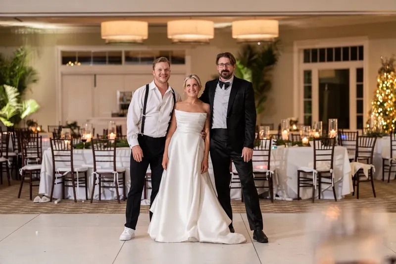 Ashley and Craig stand together at the center of the reception hall with groomsmen flanking them.