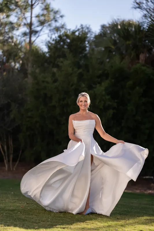 Ashley twirls in her flowing white ball gown, the skirt billowing as she moves across the lawn.