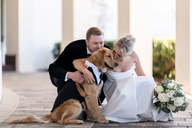 The couple laughs while their dog licks Ashley's face during an outdoor portrait session.