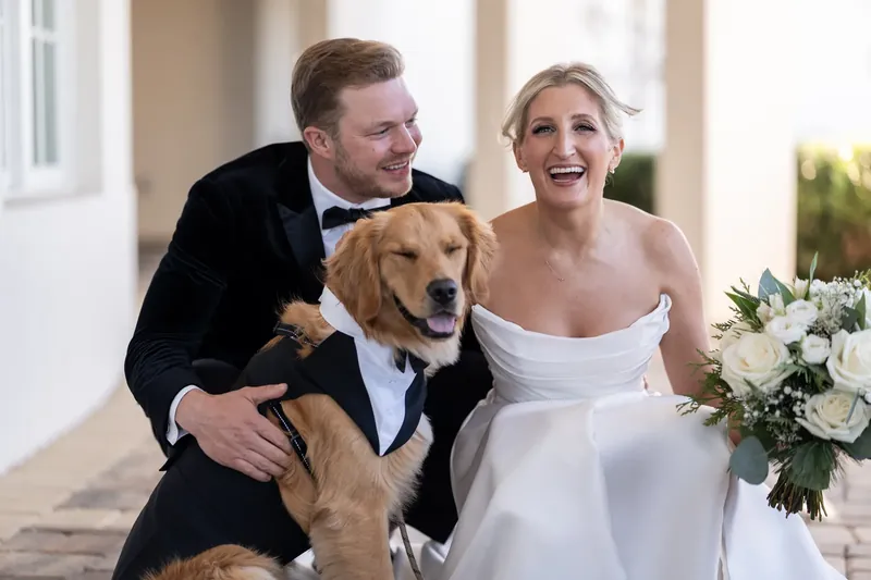 Craig and Ashley cuddle their golden retriever between them, both beaming at the camera.