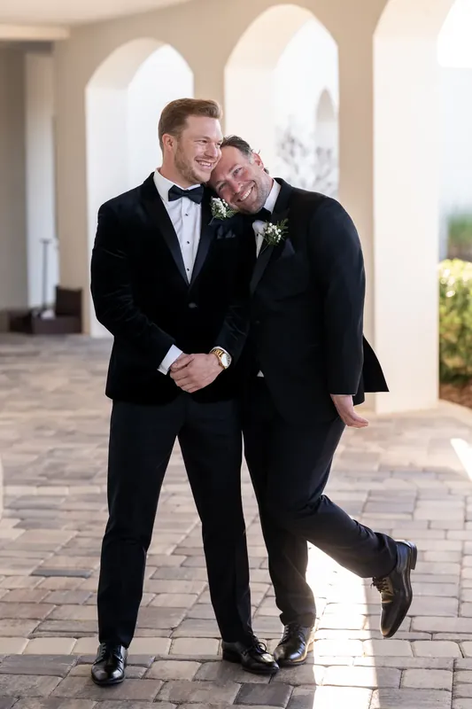 Craig and a partner walk arm-in-arm down a sunlit colonnade, both smiling.