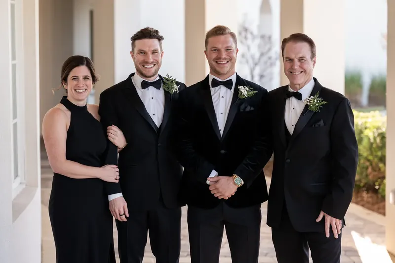 Craig stands with three groomsmen in formal black attire and boutonnieres on the covered portico.
