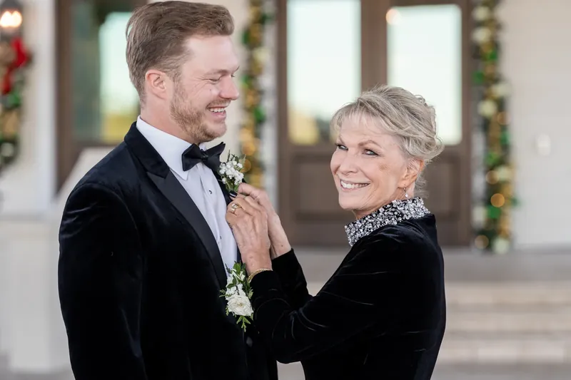 Craig adjusts Ashley's boutonniere while she smiles at the Sawgrass Marriott, framed by holiday garland.