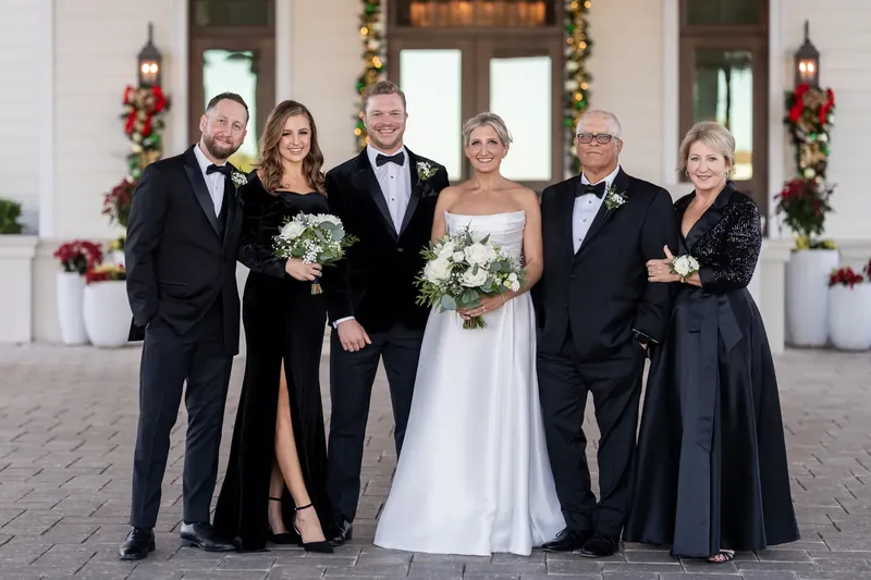 The wedding party of six stands together on the resort's terrace, holding white florals.