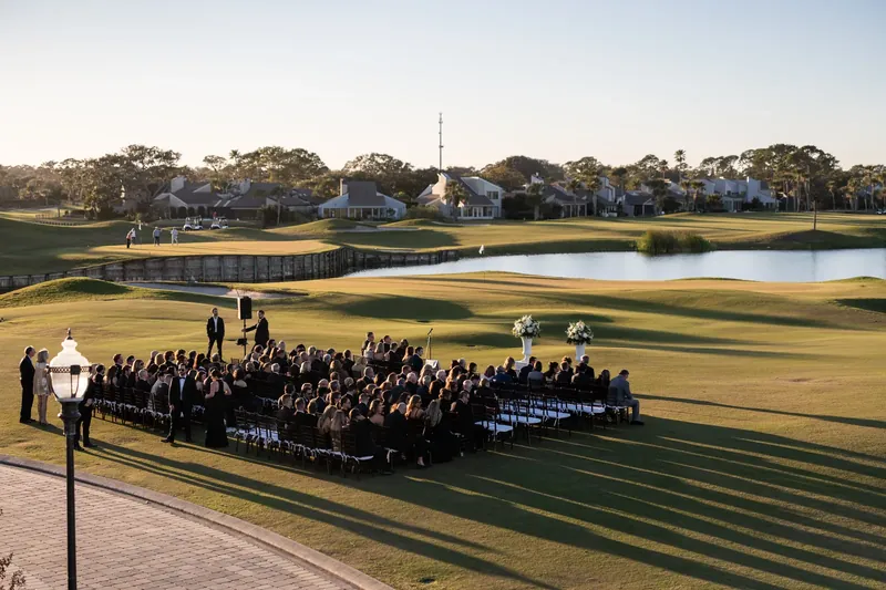 Ceremony guests stand on the golf course as Ashley and Craig's wedding begins by the water at Sawgrass Marriott.