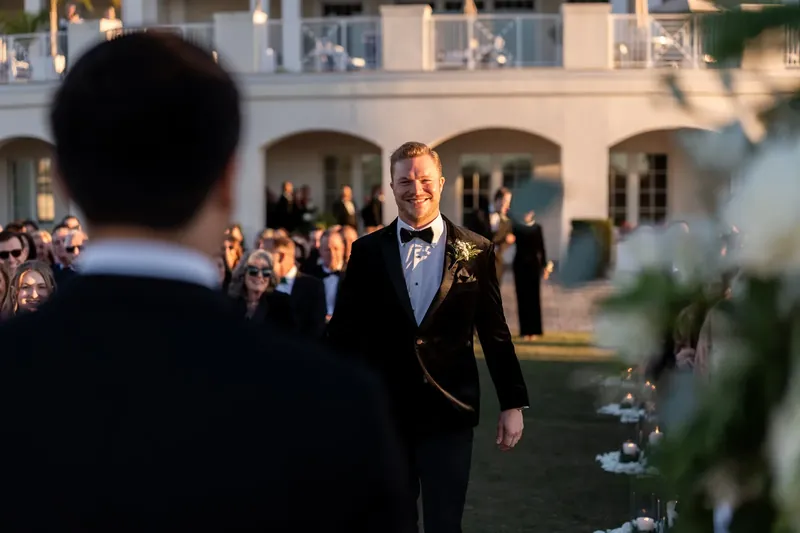 Craig walks toward assembled guests on the resort courtyard lawn during the ceremony processional.