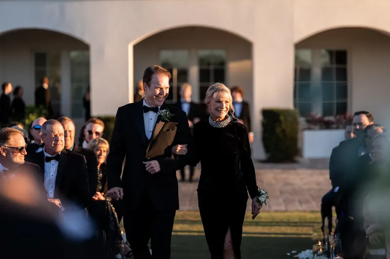 Craig and a family member walk together across the manicured grounds as onlookers gather.