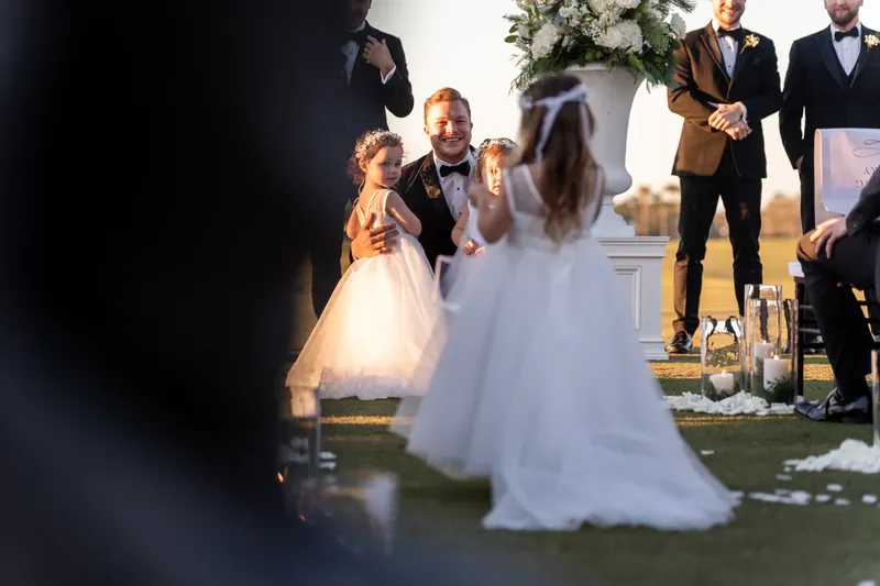 Ashley and Craig exchange vows on the grass while family and wedding party members watch during the outdoor ceremony.