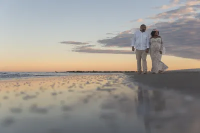 Couple walking hand-in-hand on Vilano Beach with reflection in wet sand at sunset