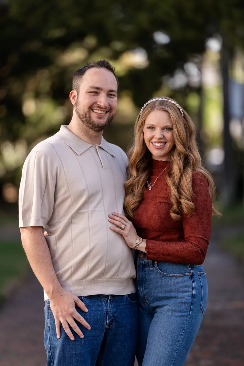 Ashley and Jordan share a warm embrace and genuine smiles during their outdoor family session, dressed in coordinating fall colors.