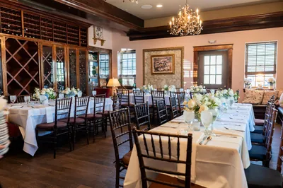 Elegant dining room at The Chatsworth Pub and Tea Room with cream linens, black chairs, and white floral centerpieces