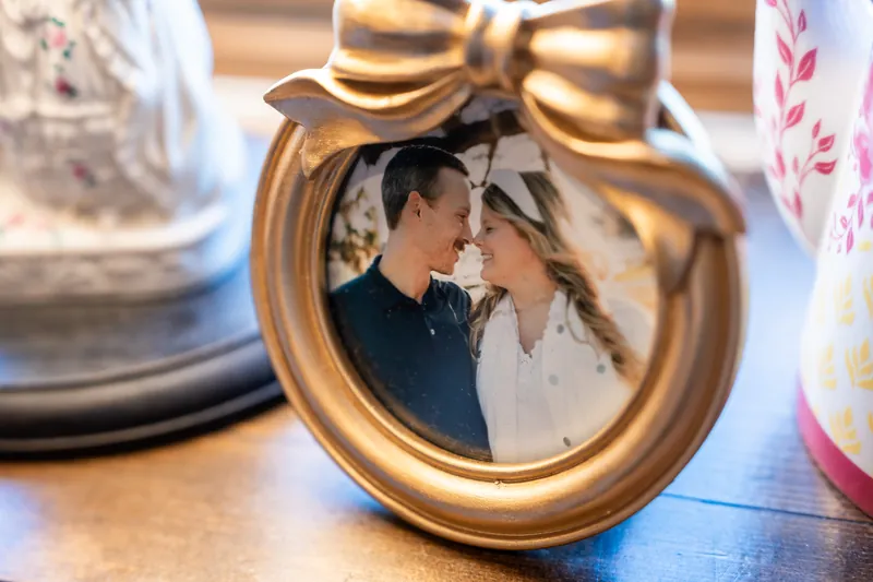Ashley and Jared smile at each other inside a gold-rimmed ornament displayed on the table at The Chatsworth Pub and Tea Room.