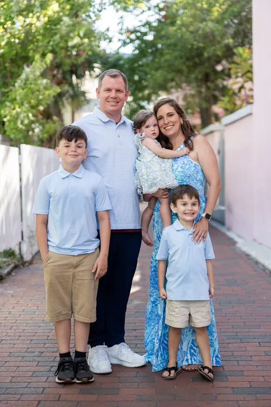 An adult and three children stand together on a brick pathway lined with greenery outside the venue.