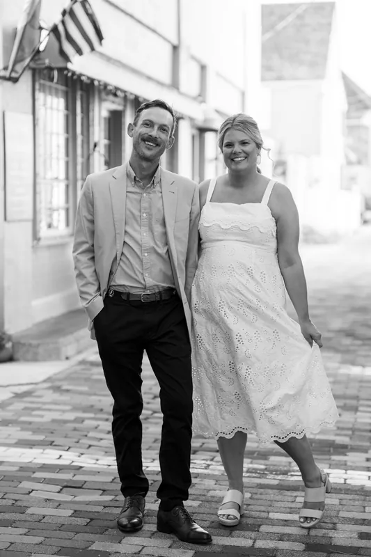 In black and white, Ashley and Jared walk together down a quiet brick pathway in Downtown St Augustine, both beaming.