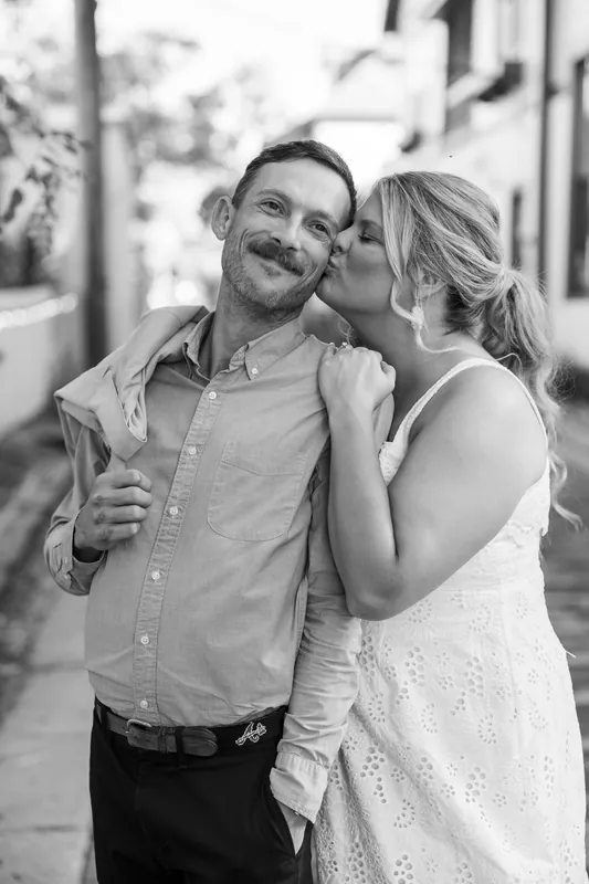 Jared smiles as Ashley kisses his cheek on a peaceful Downtown St Augustine brick alley.