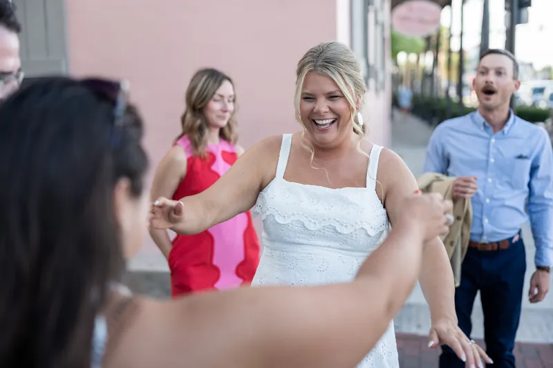 Ashley laughs while interacting with guests on a Downtown St Augustine street, surrounded by friends in casual celebration.