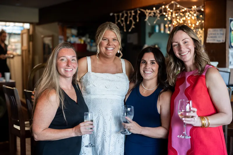 Four women hold drinks and smile together at The Chatsworth Pub and Tea Room.