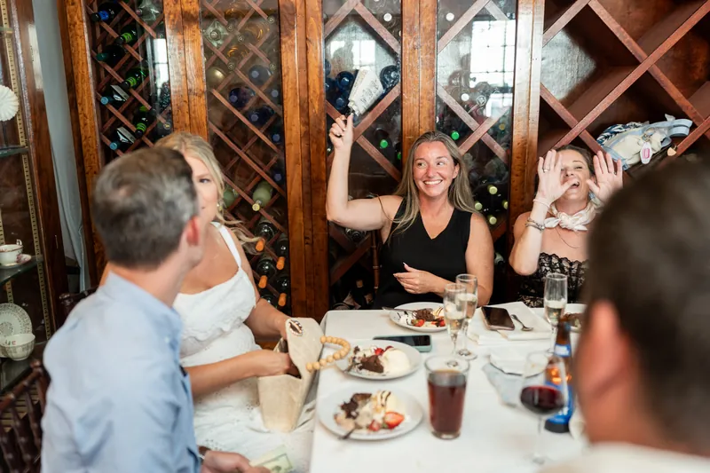 A guest raises her arms enthusiastically while seated at the dining table during the celebration.