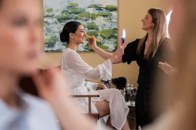 Makeup artist applying makeup to bride in preparation room before wedding