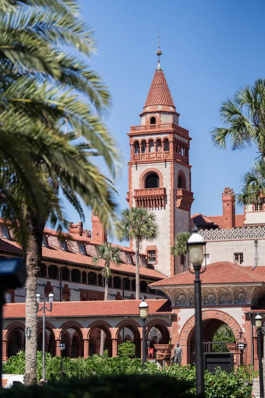 Red-tiled bell tower and terra-cotta buildings frame palm trees under clear blue sky at the museum.