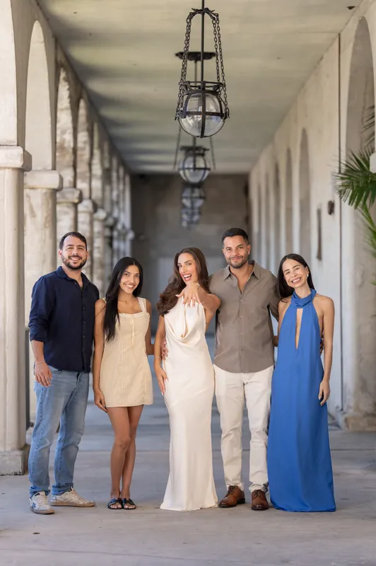 Five people stand together under a hanging lantern along the arched colonnade at Lightner Museum Courtyard, one wearing a flowing white gown.