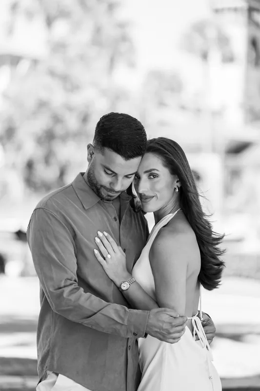 In black and white, the two hold each other close with soft focus greenery behind them in the courtyard.