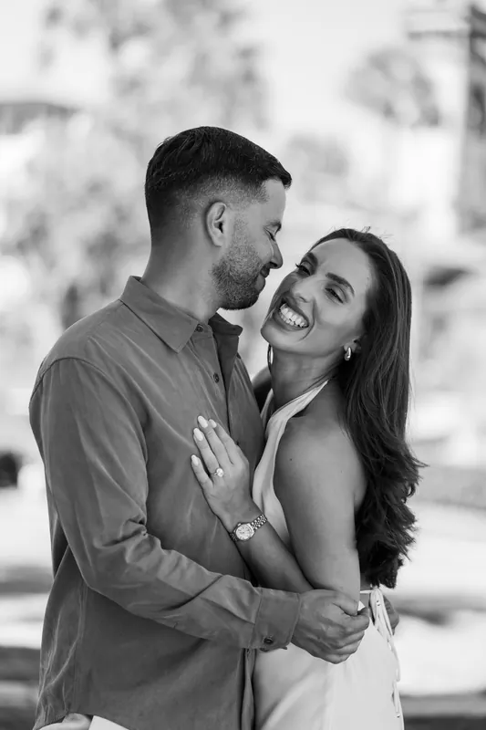 Beltran and Gabriela embrace and laugh together in the Lightner Museum Courtyard, with soft architectural details blurred behind them.