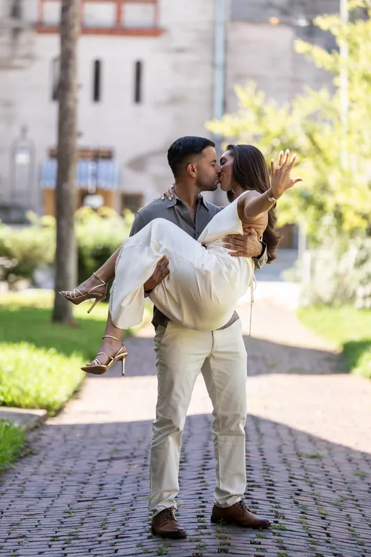 Beltran lifts Gabriela in a joyful embrace on a brick pathway at Palm Row, St. Augustine, with historic architecture glowing behind them.