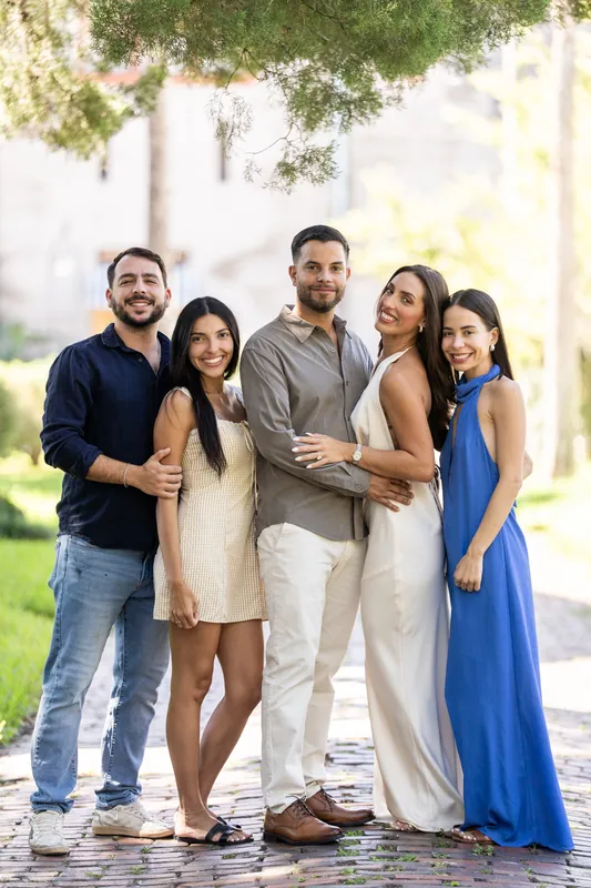 Six people gather on the brick pathway at Palm Row, posing together to commemorate the proposal with genuine smiles.