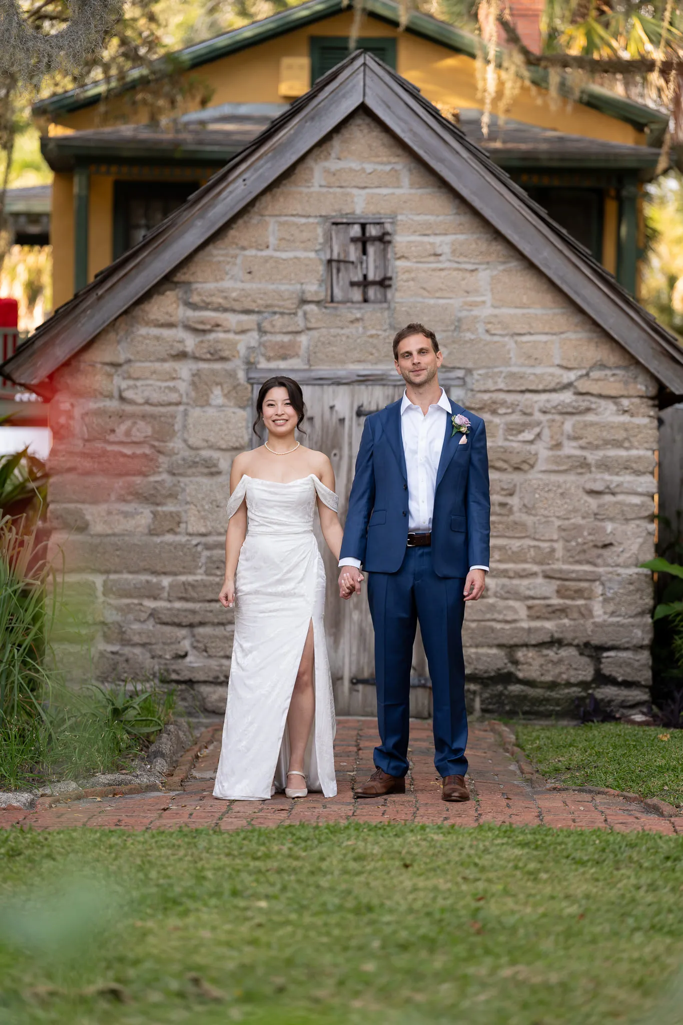 Bride and groom holding hands outside historic stone chapel building