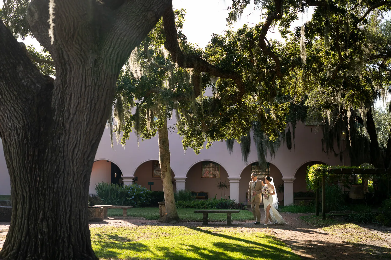 Binh and Nico walking together under oak tree with Spanish moss at the Oldest House