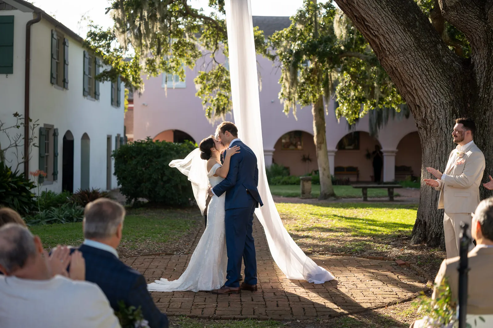 First kiss wide shot under oak tree at the Oldest House wedding