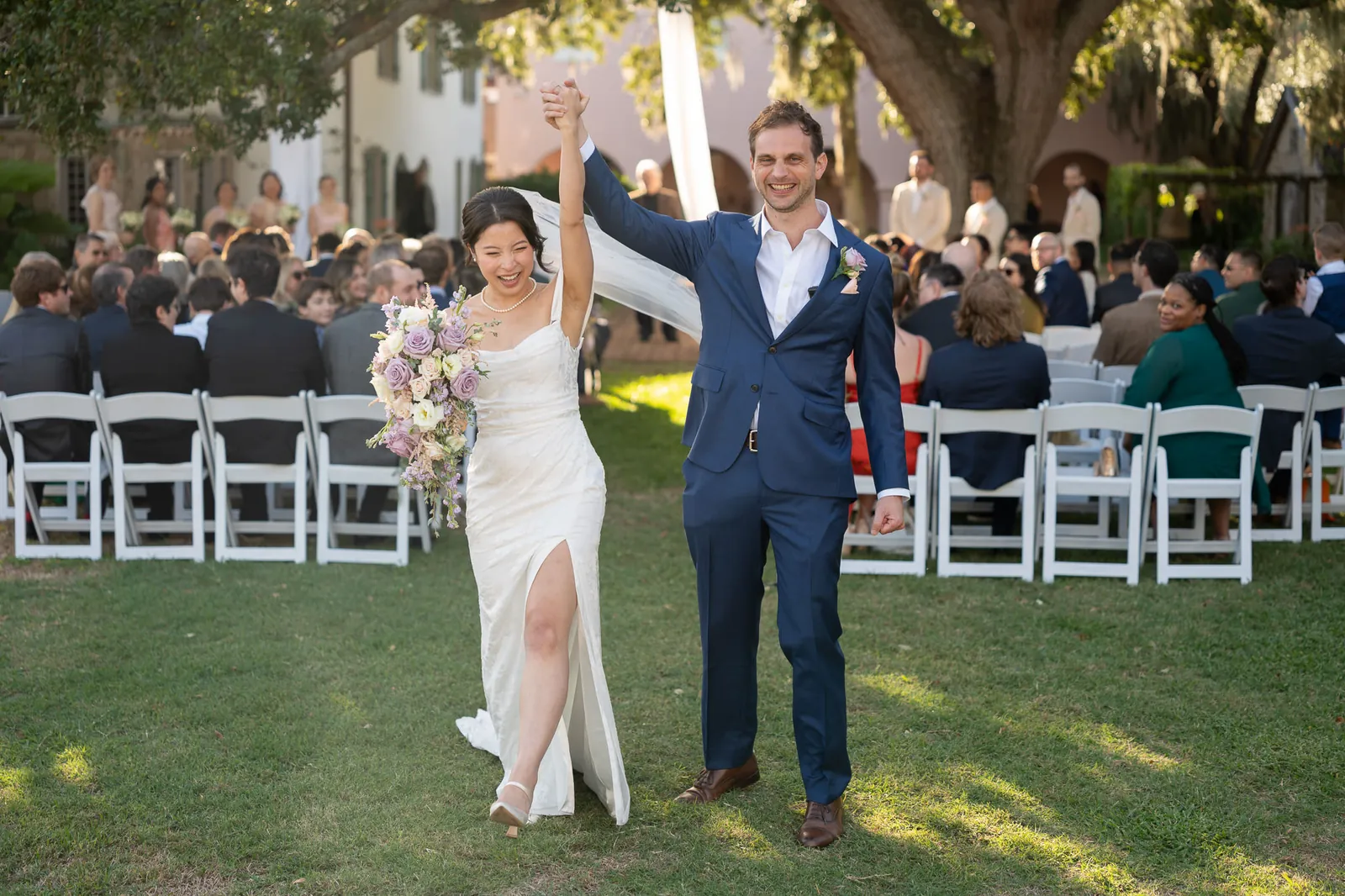 Binh and Nico recessional with arms raised celebrating at the Oldest House
