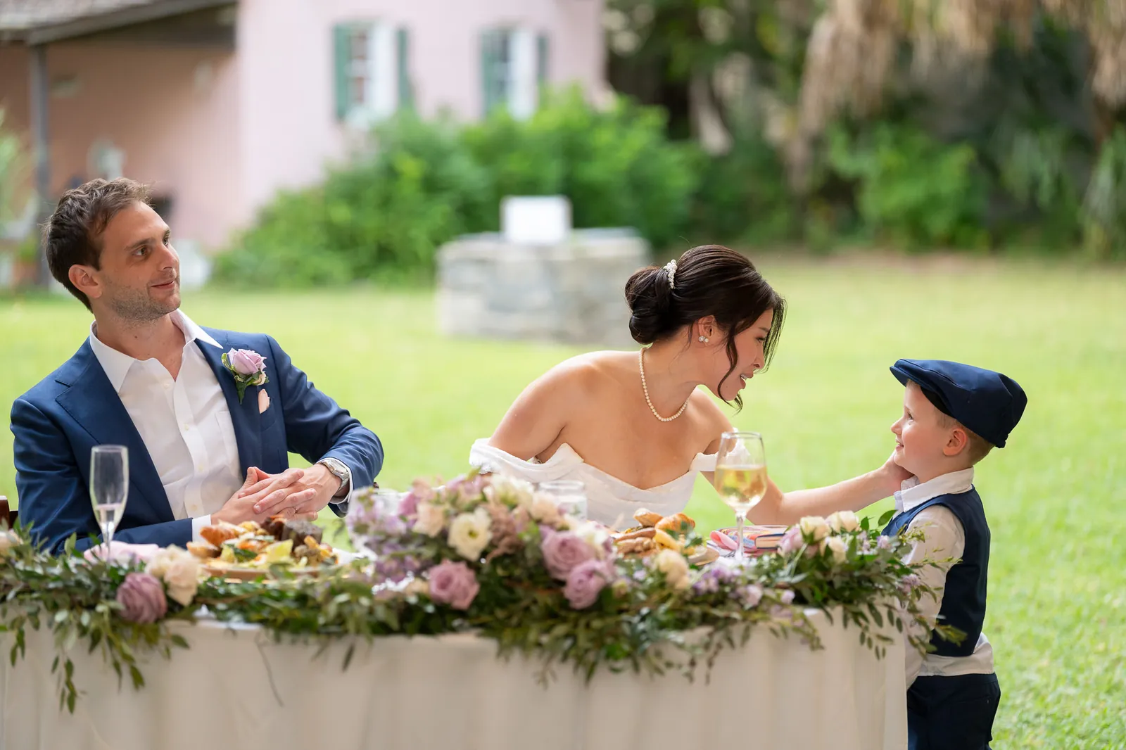 Ring bearer in flat cap toasting bride Binh at the sweetheart table