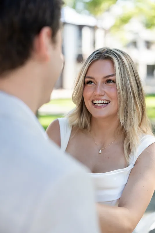 Devin smiles at Blair, who wears a white sleeveless dress, during their ceremony at St. Francis Park.