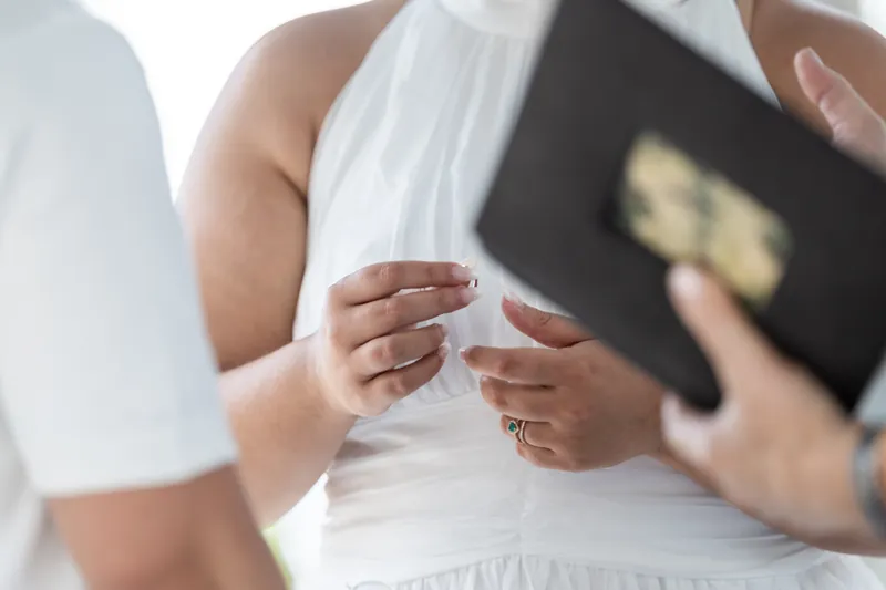Blossom's hands hold an open black book during the ceremony.