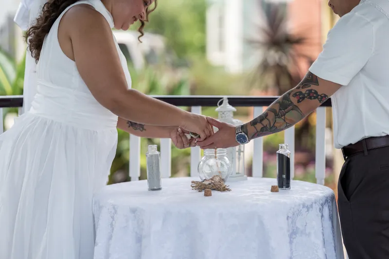 Chris and Blossom clasp hands over a marble table set with candles at Bayfront Marin House.