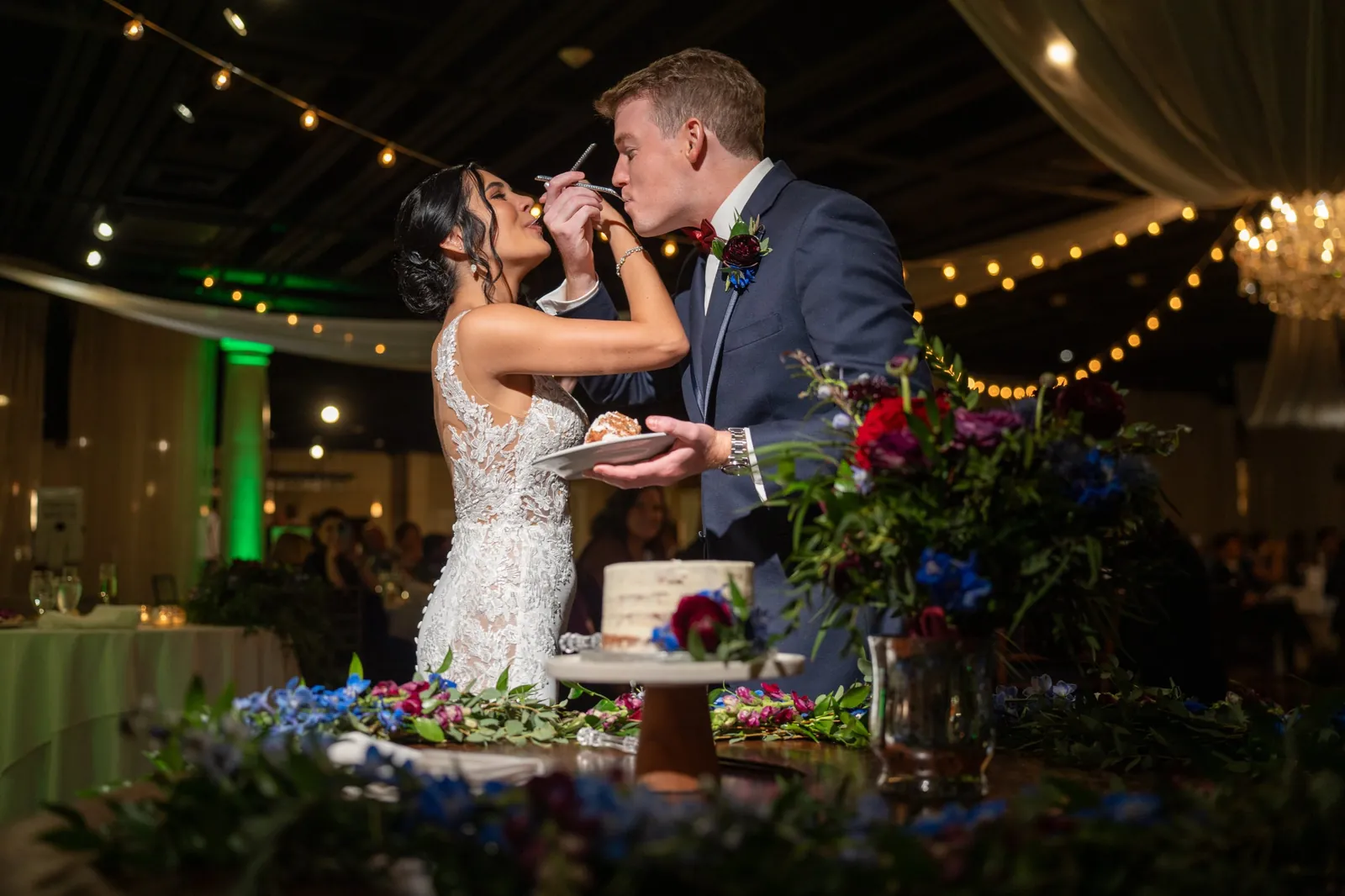 Bri and Nick cake cutting with jewel tone flowers at The White Room
