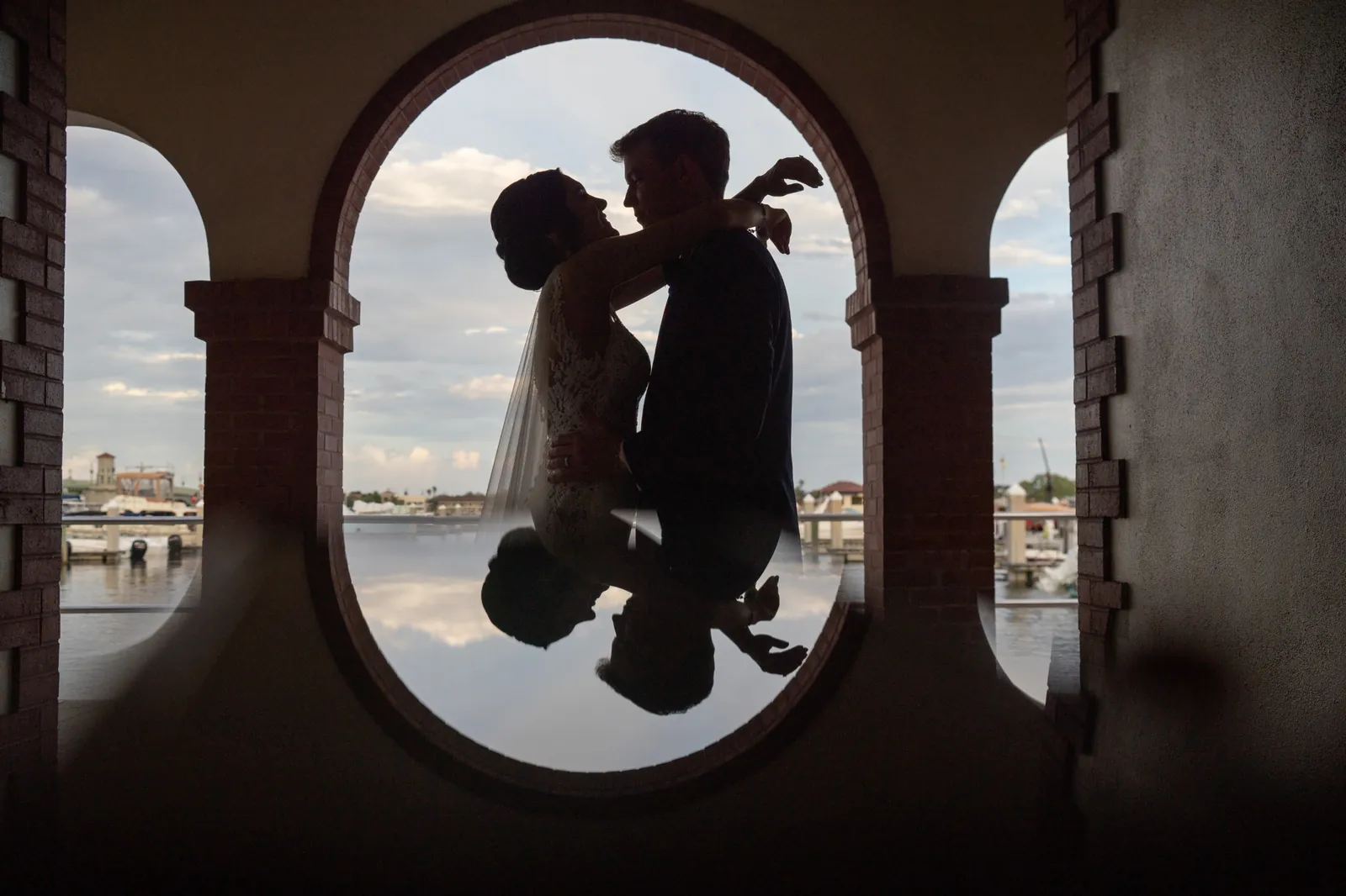 Bri and Nick silhouette in brick arch with bayfront reflection at The White Room