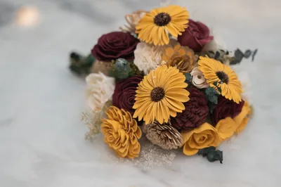 Bridal bouquet with yellow gerberas, burgundy roses on marble surface
