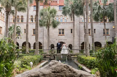 Bride and groom on courtyard bridge at Lightner Museum with palm trees