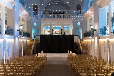 Lightner Museum ballroom ceremony setup with string lights and grand staircases