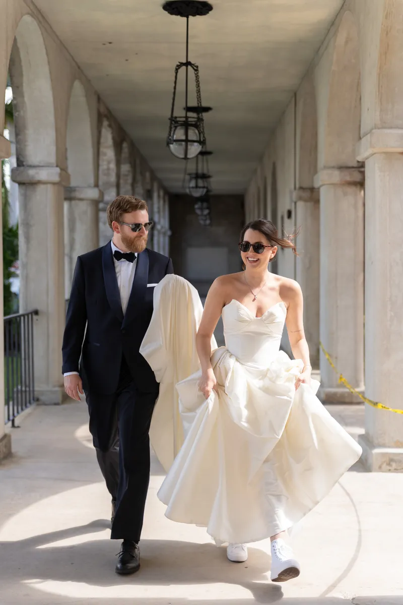 Bridey twirls in her flowing white gown beneath a pergola at the Lightner Museum, her dress catching the motion.