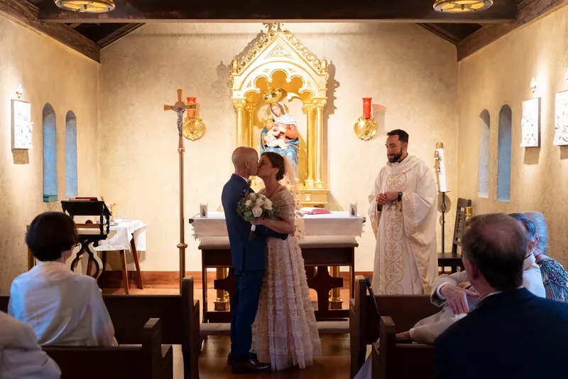 A videographer captures the moment as Bridgid and Dan kneel together before the golden shrine altar.