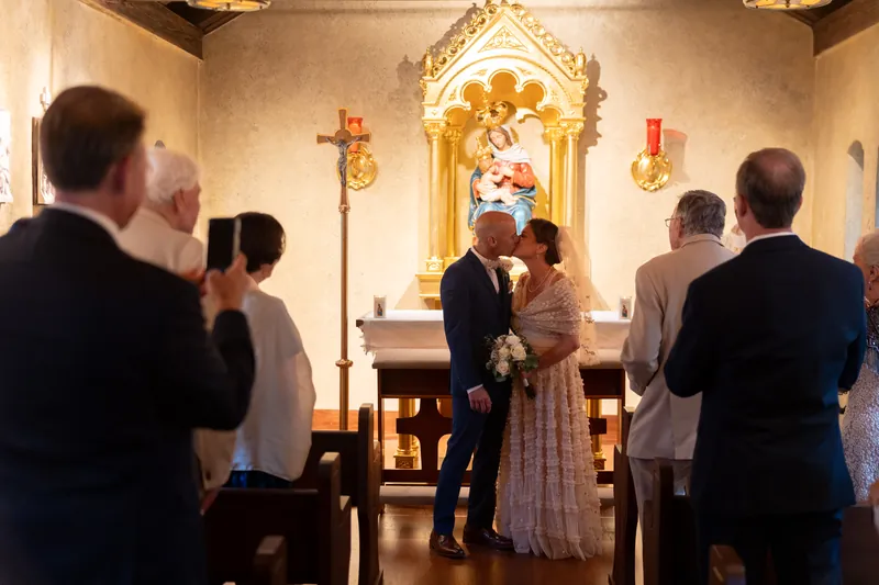 Bridgid and Dan stand before the altar at Mission Nombre de Dios, exchanging vows as witnesses look on.