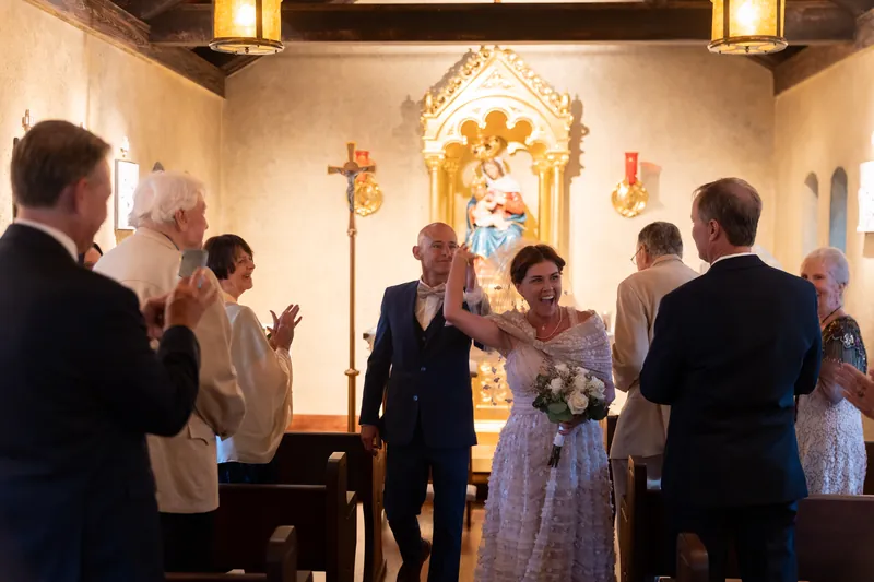 The couple joins hands at the shrine's ornate altar while family and friends observe the ceremony.