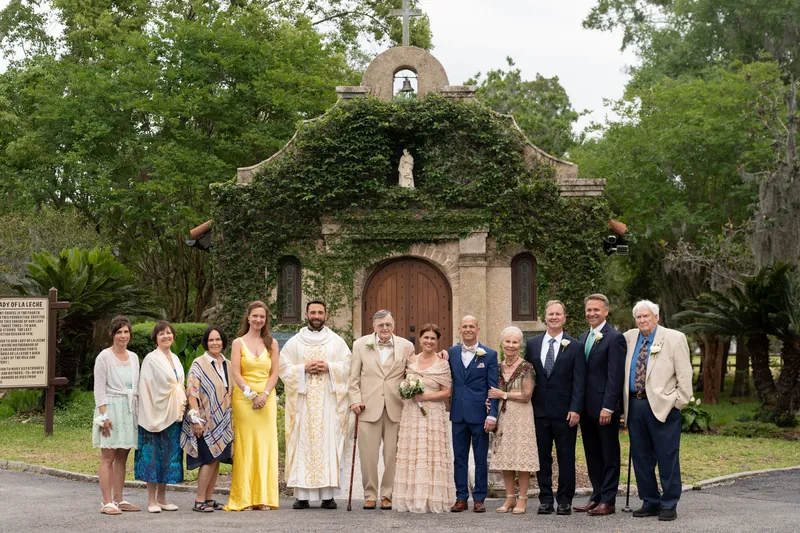 Wedding guests in formal and pastel attire line up for a group portrait at the shrine.