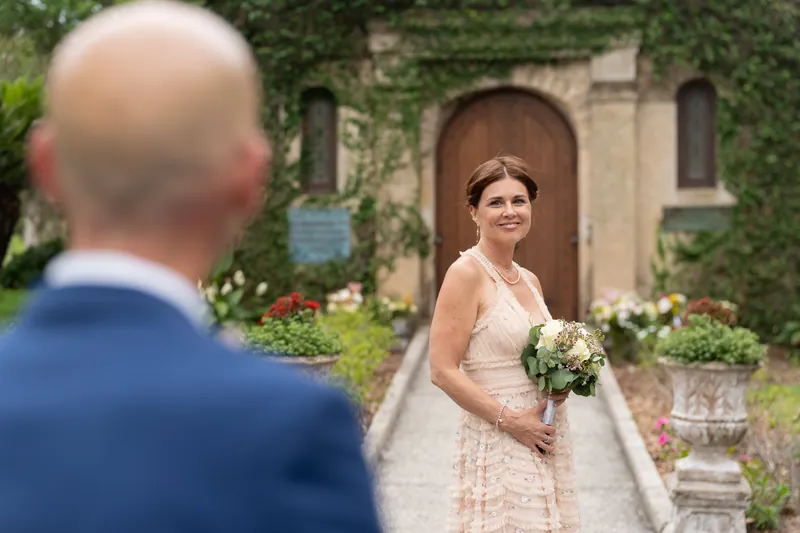 Dan in navy faces away as Bridgid waits with her flowers, the mission's arched entrance framing the moment.